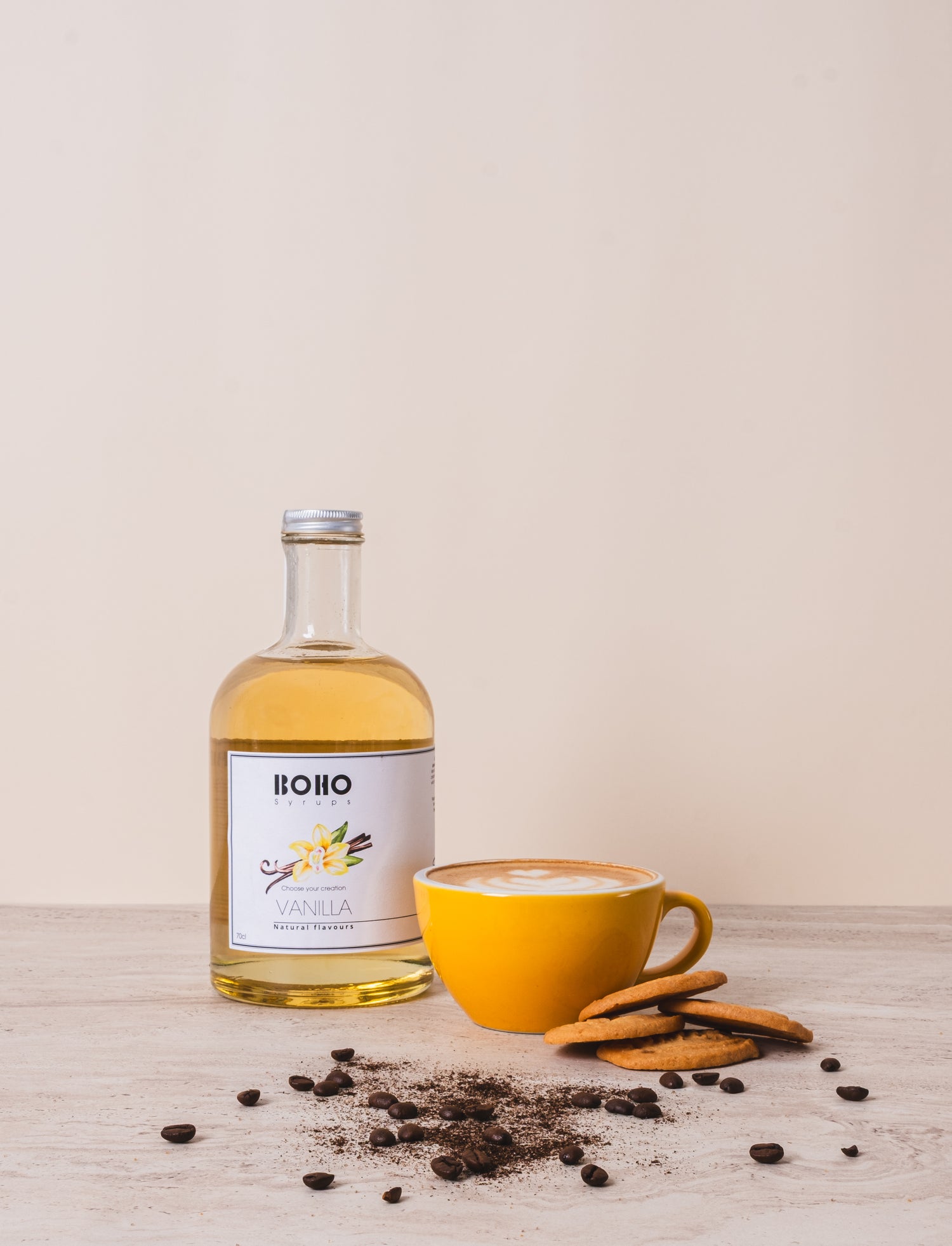 Grote fles BOHO vanille siroop met een cappuccino ernaast – romige koffie met een zachte vanilletoets